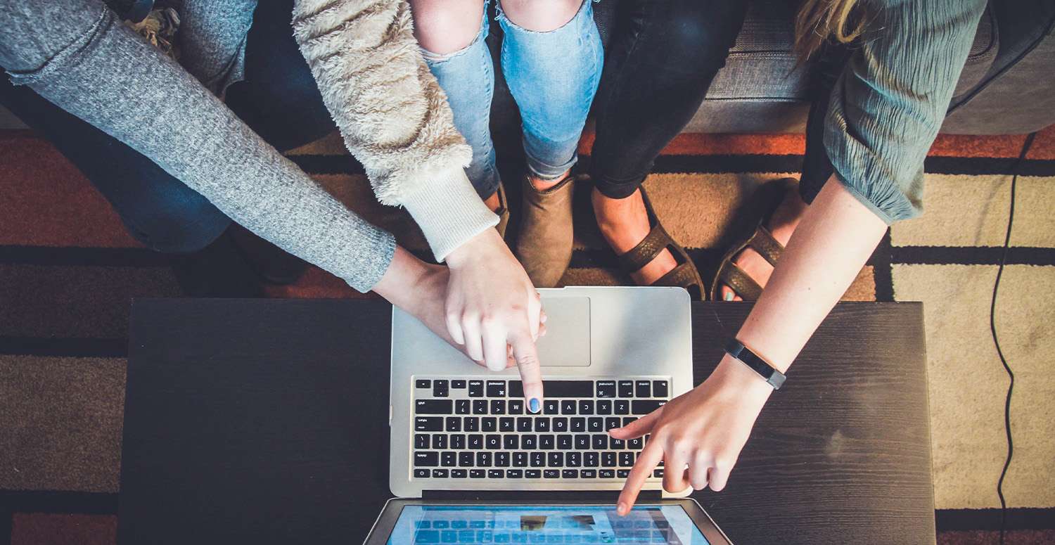 Group of people sitting on couch pointing at laptop screen